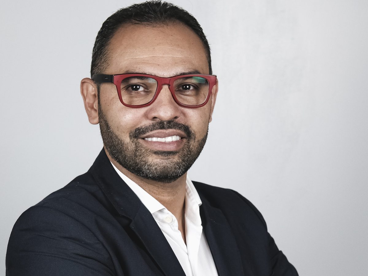 Fernando Bacelar sorrindo, de braços cruzados
